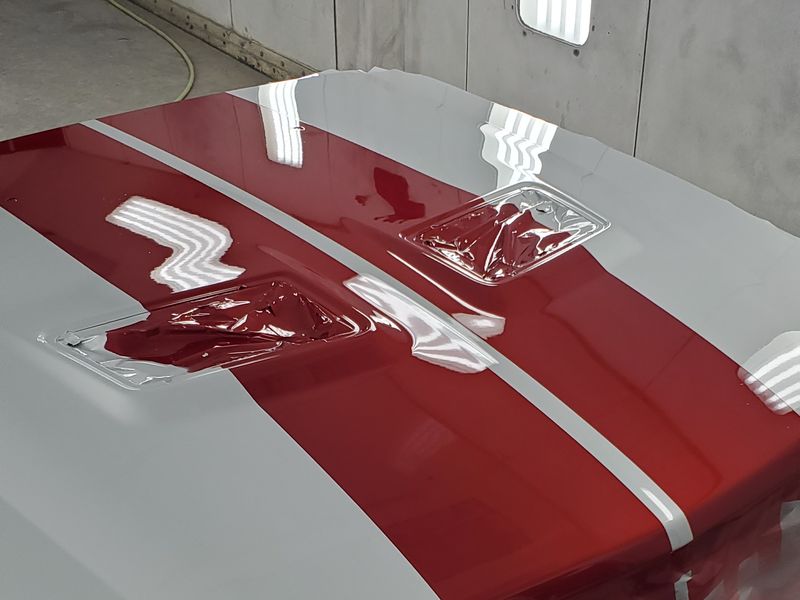 The Mustang's hood after refinishing, the red stripe matched across the panel.