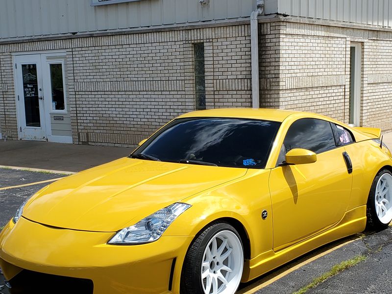 The same Nissan 350Z outside the shop in fresh gloss yellow after a complete repaint.