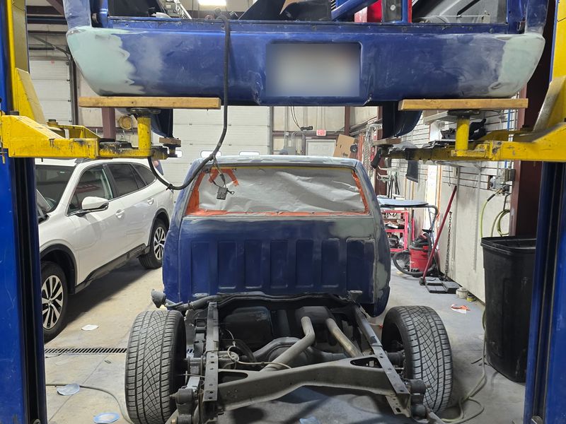A Chevrolet pickup stripped down on the lift, bed off, before a complete repaint.